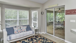 A living room with a sofa, a patterned rug, and a sliding glass door leading to a patio. - Your home away from home! Pet friendly & 5 minutes from WEC. (Ocala)