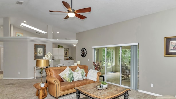 A spacious living room with a leather sofa, a coffee table, and a ceiling fan. - Your home away from home! Pet friendly & 5 minutes from WEC. (Ocala)