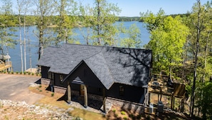 A house with a stone foundation, a dark roof, and a stone-paved driveway. - Lakeside Cottage in the Treetops - 2 bedrooms with amazing view (Jacksons' Gap)
