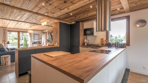 A modern kitchen with wooden beams, a central island, and a view of the outdoors.