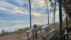 Ein Picknick am Strand mit Tisch, Bänken und Grill, mit Blick auf den Ozean.