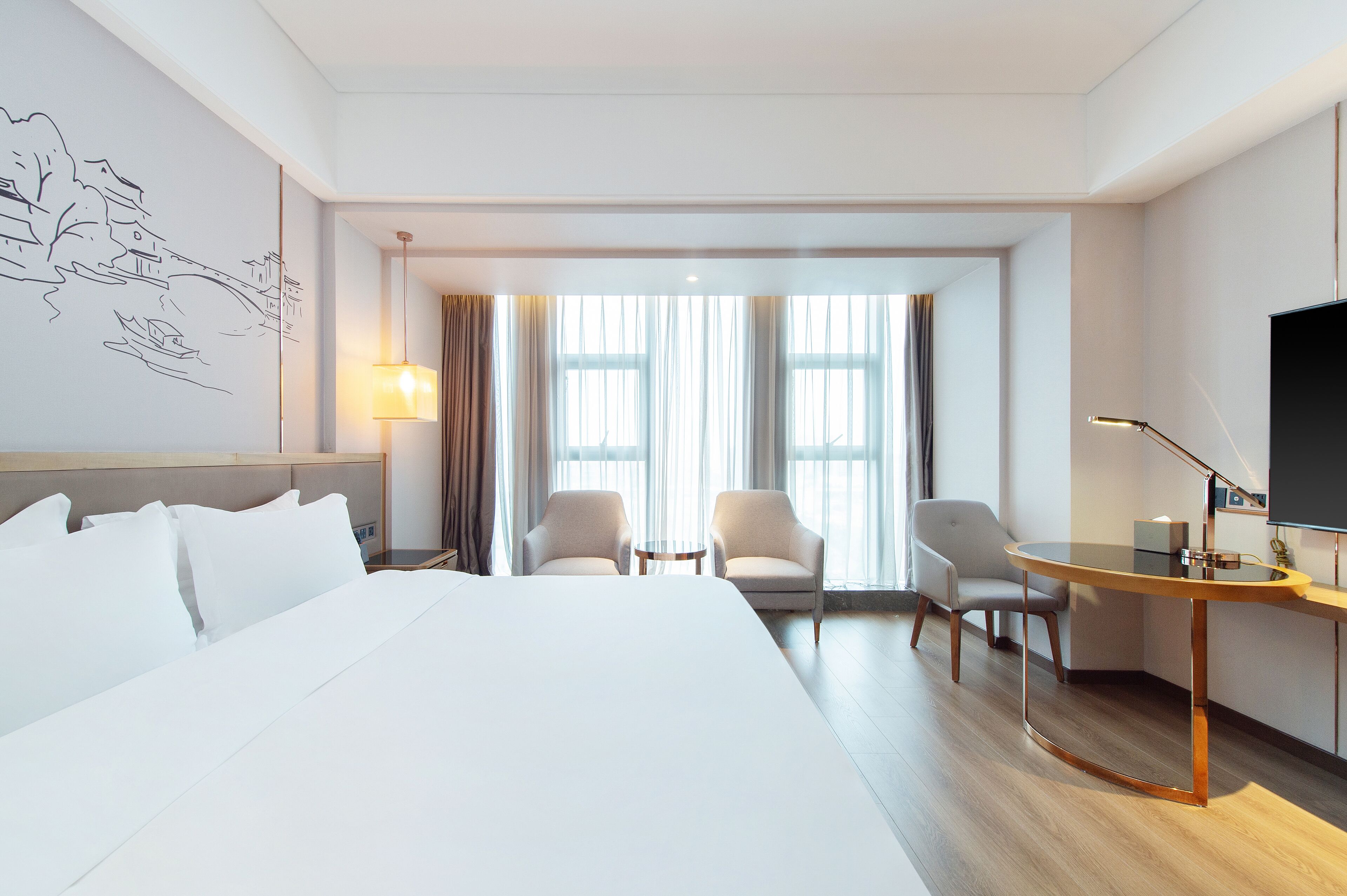 Et moderne hotelværelse med en stor seng, to lænestole, et lille bord og et fjernsyn.