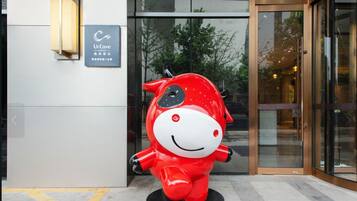 Una estatua roja de mascota frente a un edificio con un cartel que dice 'UrCove'.