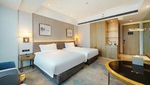 A hotel room with two beds, a desk, a chair, a small table, and a bathroom with a mirror and towel rack. - UrCove Hefei Eco-Tech Development Area (Hefei)