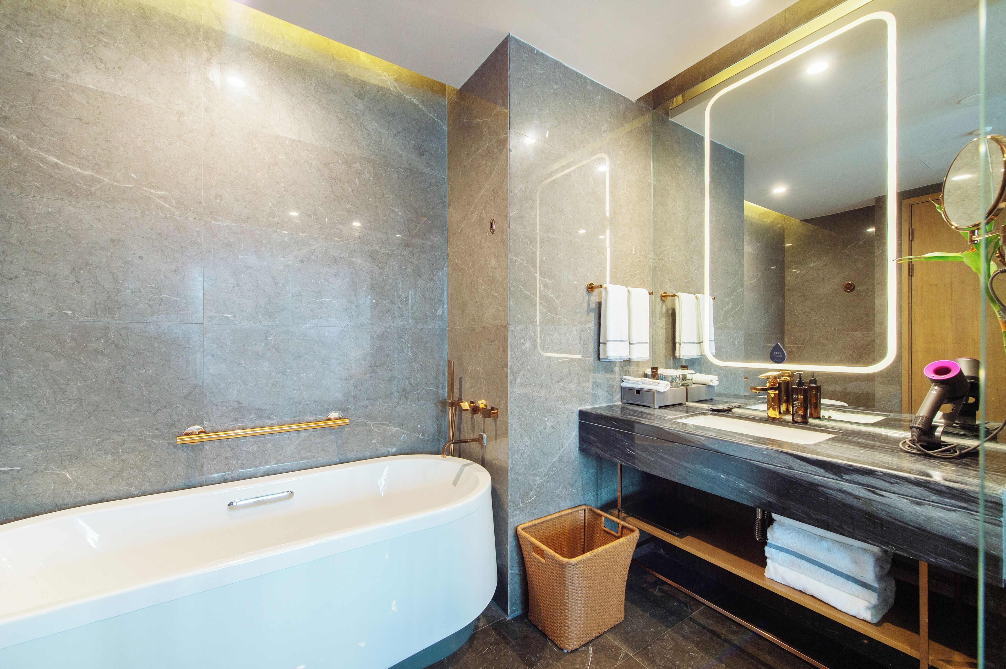Un bagno moderno con una vasca freestanding, un mobile vanitario con specchio e un box doccia in vetro.