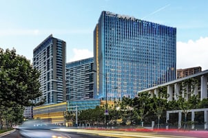 A modern high-rise building with a glass facade, multiple floors, and a prominent signage at the top.