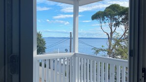 A covered porch with a white railing, overlooking a body of water and trees. - Mediterranean, coastal retreat in the heart of Toukley. (Toukley)