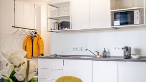 Moderni keittiö, jossa on valkoiset kaapit, mikroaaltouuni ja vedenkeitin työtasolla.
