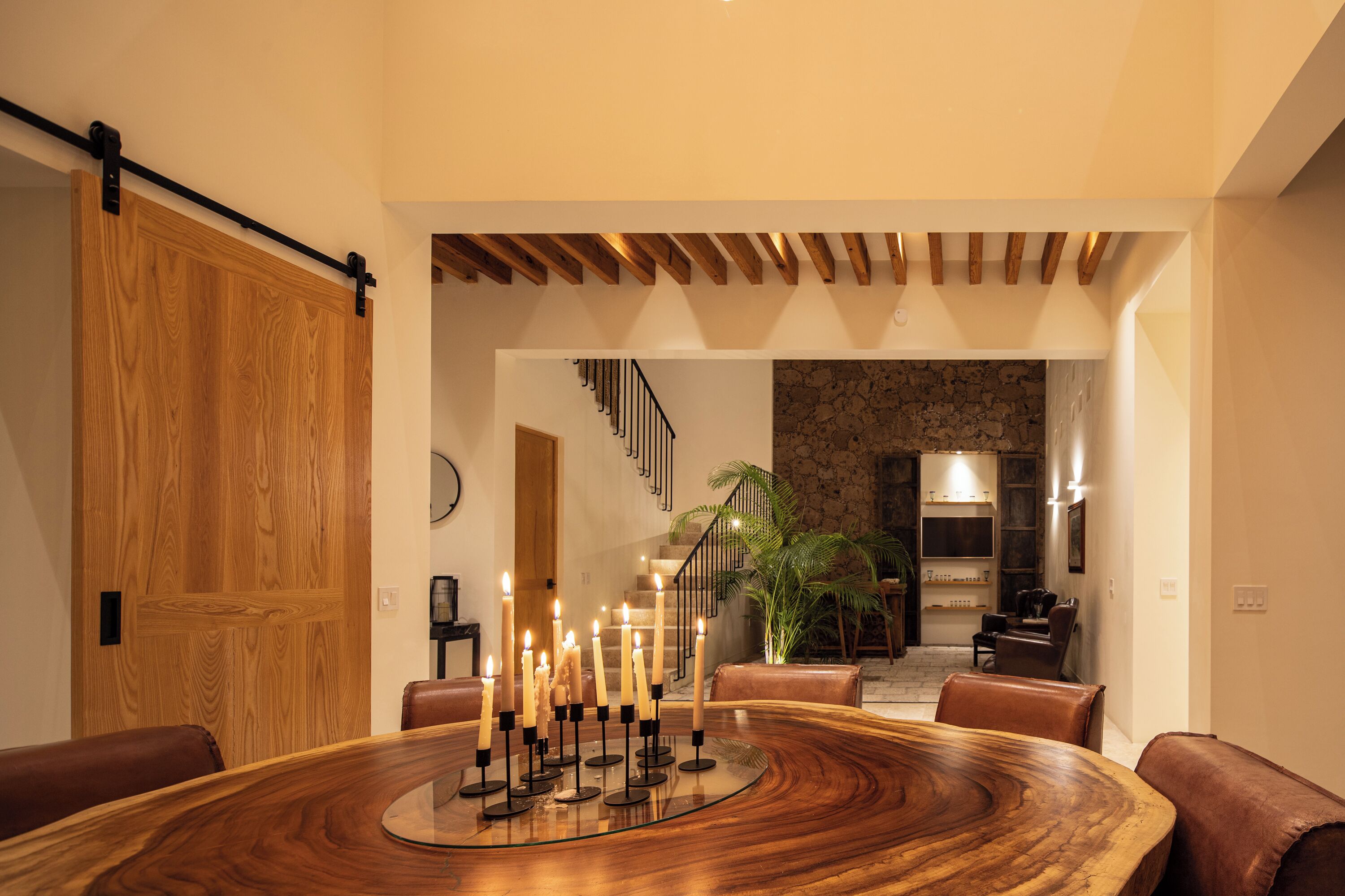 Un coin repas avec une table en bois, des bougies et des chaises en cuir.