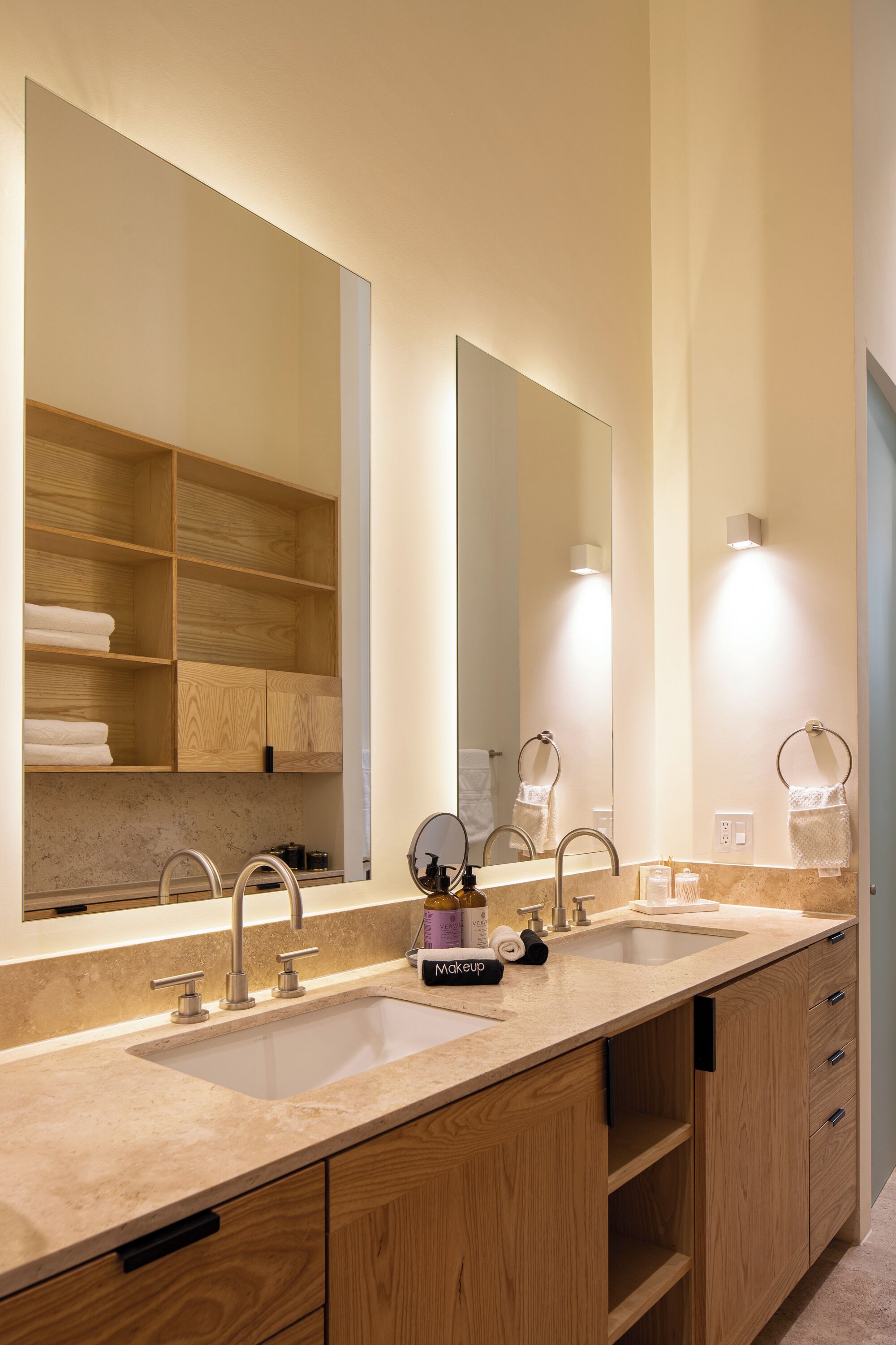 A modern bathroom with a double sink, wooden cabinetry, and a large mirror.