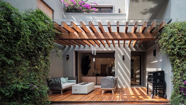 A modern outdoor patio with wooden flooring, a built-in seating area, and a pergola.