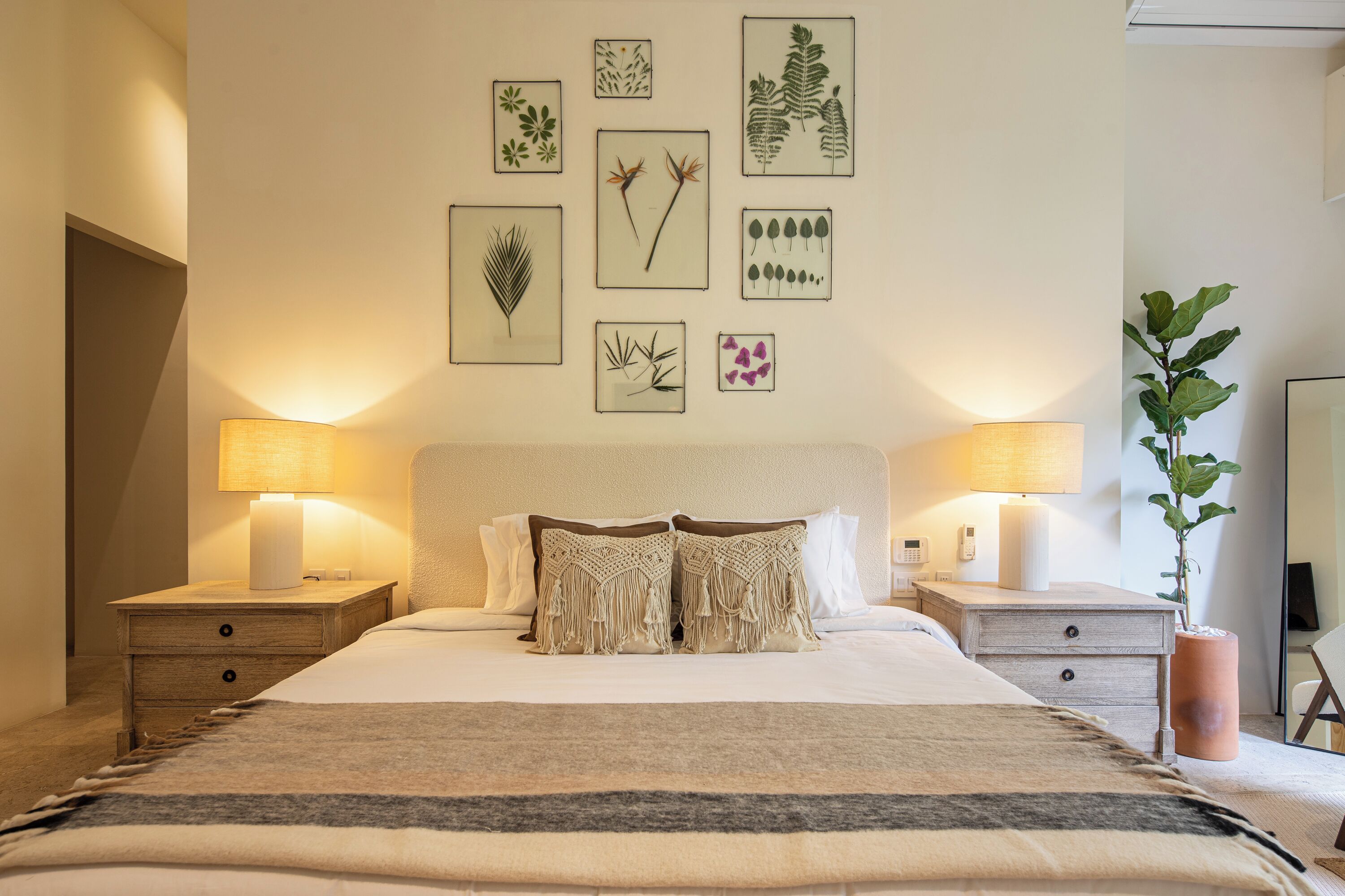Quarto bem arrumado com uma cama grande, duas mesas de cabeceira e uma parede decorada com gravuras botânicas emolduradas.