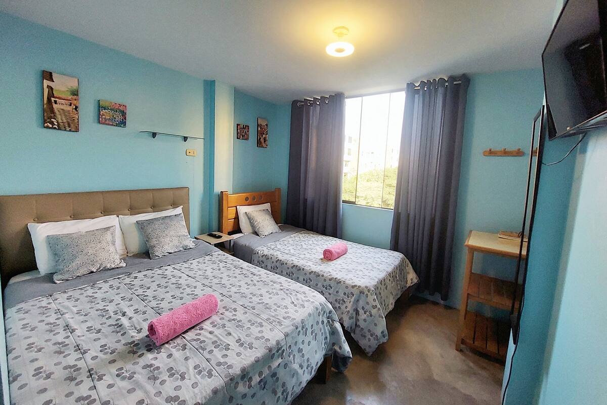 A room with two beds, a TV, and a window with curtains.