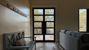 Een kamer met een bank, een sofa en een groot raam met veel ruiten.