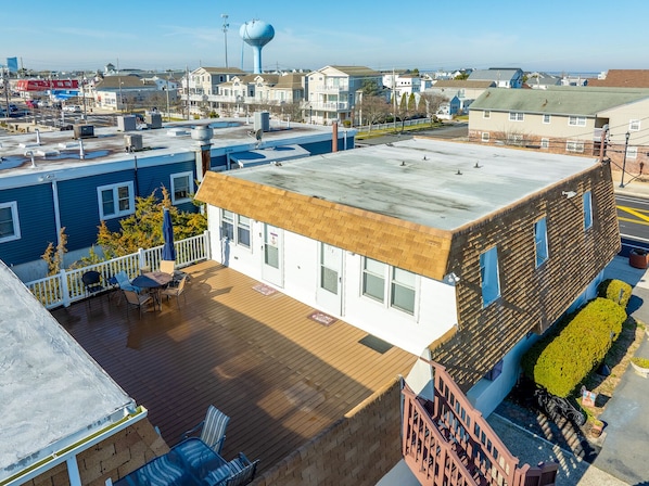 Un immeuble à plusieurs étages doté d’une terrasse sur le toit, avec un château d’eau en arrière-plan et une vue dégagée sur le quartier environnant.