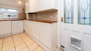 A kitchen with white cabinets, a wooden countertop, and a tiled floor. - Charming Period Home near Surbiton with Garden (Greater London)