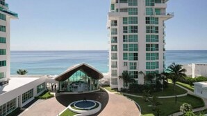 A modern hotel with a central courtyard, a pool, and a view of the ocean. - New Studio at the beach, gym, pool, spa. (Cancún)