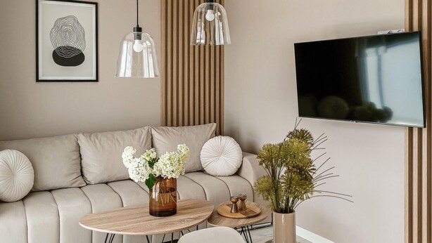 A modern living room with a beige sofa, a round wooden coffee table, and a TV mounted on the wall. - 2 bedroom gorgeous apartment in Biskupiec (Biskupiec)
