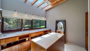 Un baño moderno con tragaluces, un espejo grande y muebles de madera.