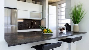 A modern kitchen with white cabinets, a black countertop, and a large window. - Esperanza Beach 2BDR 2B Oceanfront Pool (Carolina)