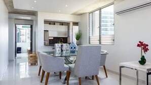 A modern kitchen with a glass dining table, grey upholstered chairs, and a marble countertop. - Esperanza Beach 2BDR 2B Oceanfront Pool (Carolina)