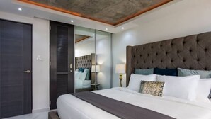 A modern bedroom with a large bed, a dark headboard, and a sliding door closet. - Esperanza Beach 2BDR 2B Oceanfront Pool (Carolina)