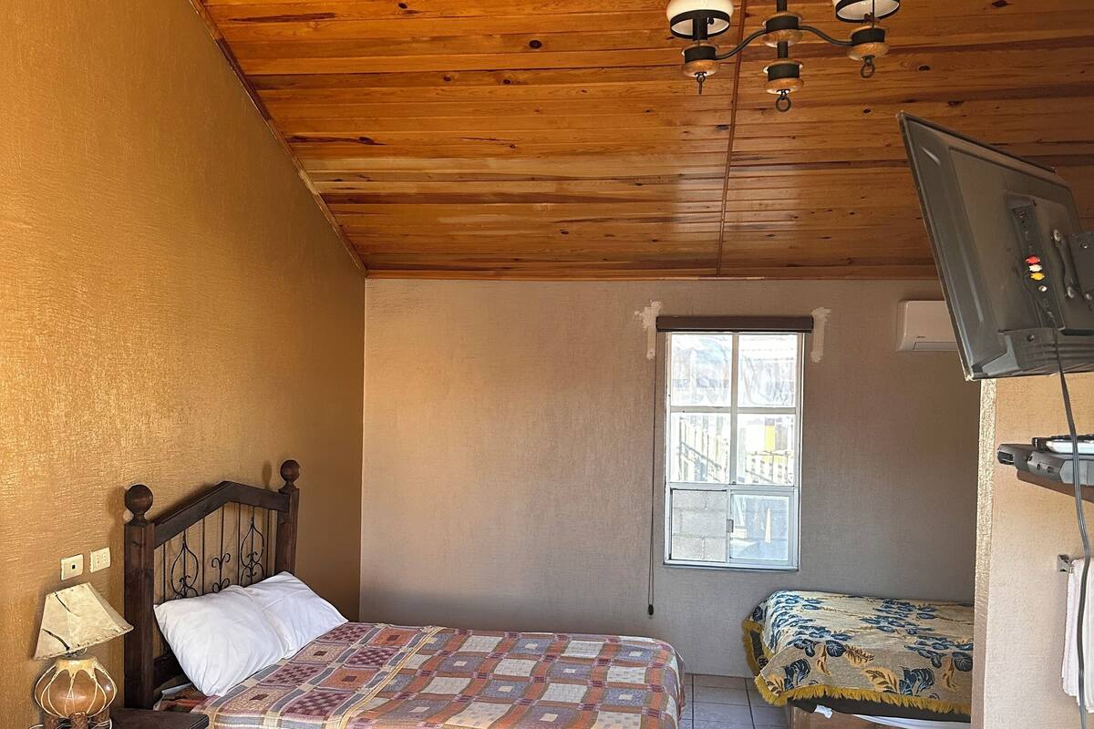 Une chambre avec deux lits, un plafond en bois et une fenêtre.
