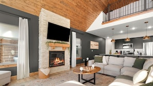 A modern living room with a fireplace, a sofa, and a coffee table. - Lakeview Cabin w/ Hot Tub, Pool, Decks - Sleeps 20 (Branson)