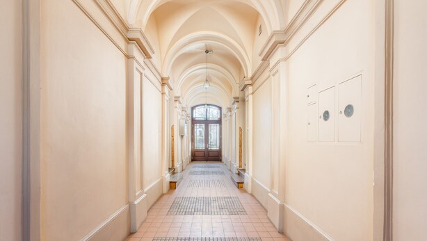 A long, narrow hallway with arched ceilings and a tiled floor.