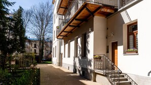 A building with a brick pathway leading to a wooden balcony with metal railings.