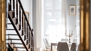 A staircase leading to a dining area with white chairs and a table.