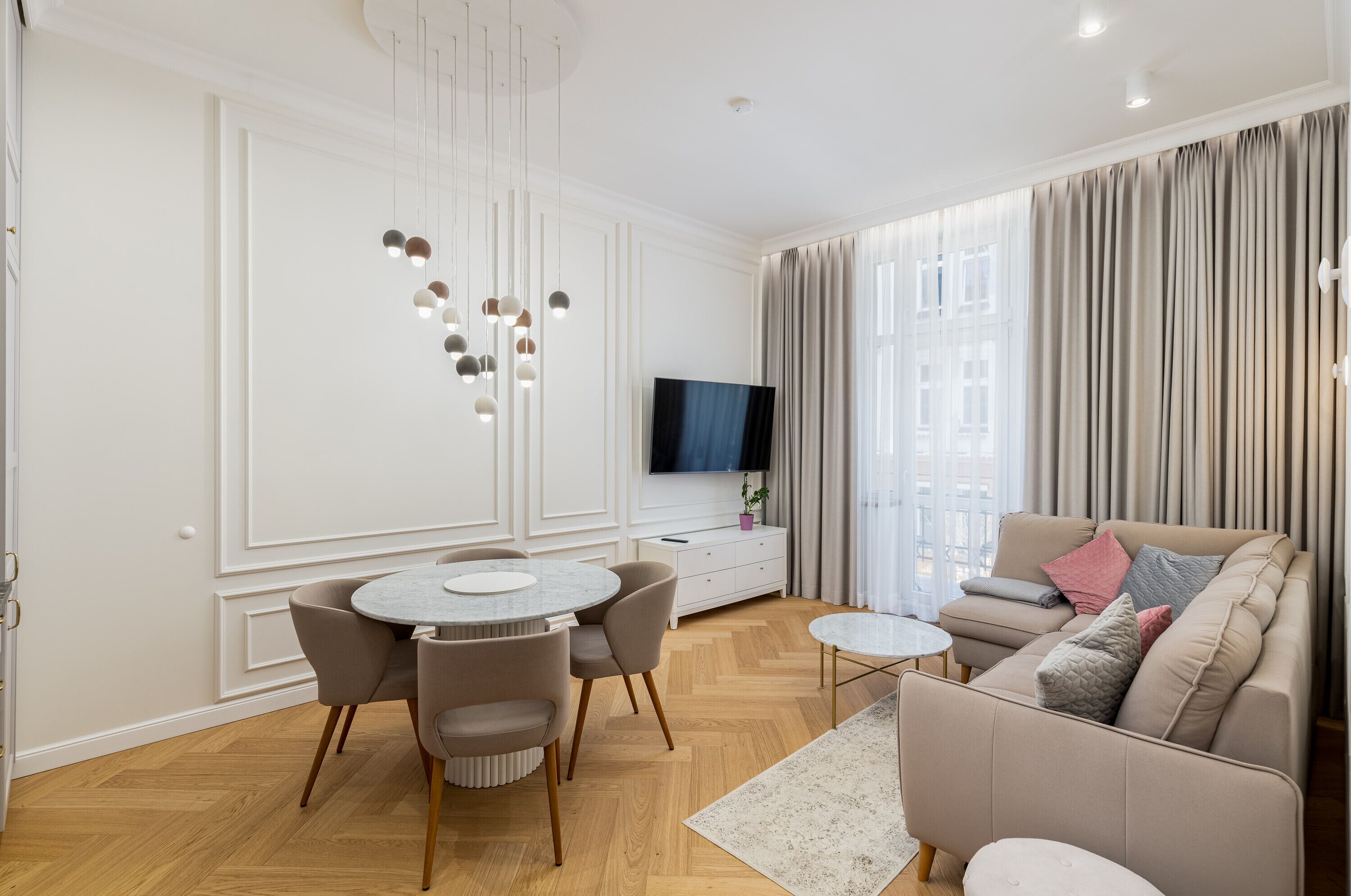 Un salon moderne avec une table à manger ronde, un canapé et un téléviseur fixé au mur.