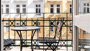Un balcon avec une table et des chaises, une vue sur les immeubles et une clôture en métal.