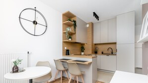 A modern kitchen with a central island, a dining area with two chairs, and a round table. - Walerego Sławka Cosy Studio (Kraków)