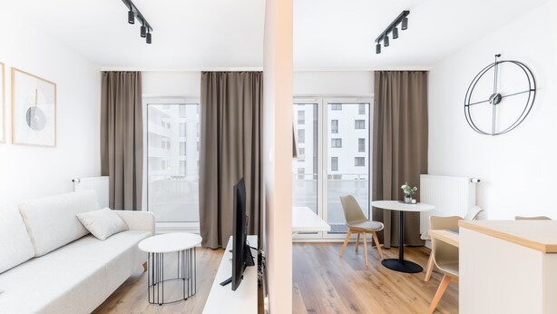 A modern hotel room with a sofa, a TV, a small table, and a desk. - Walerego Sławka Cosy Studio (Kraków)