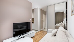 A modern living room with a flat-screen TV, a white sofa, and a small round table. - Walerego Sławka Cosy Studio (Kraków)