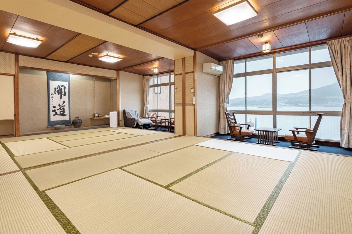 Ein traditioneller Raum mit Tatami-Matten und Meerblick, eine Tatami-Anordnung, eine Holzdecke und eine Schiebetür.