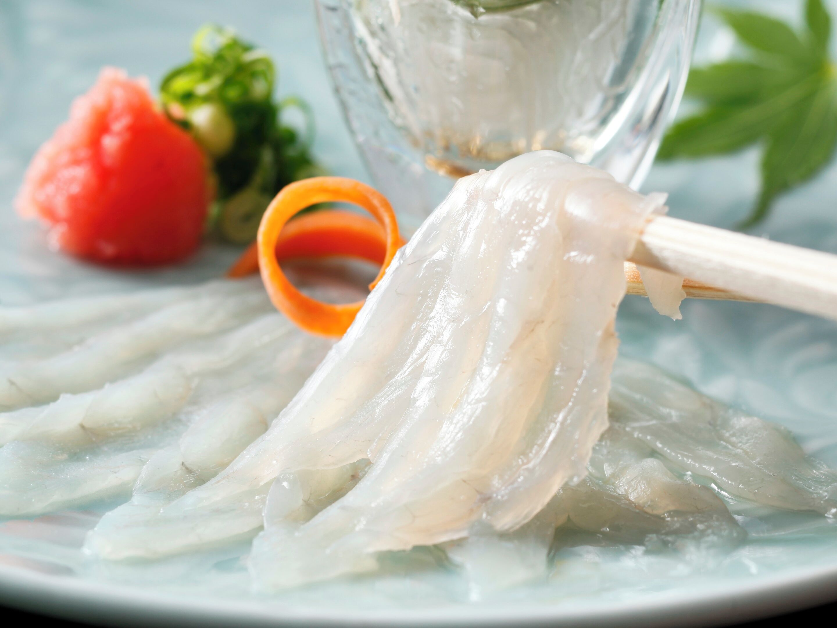 A plate with sashimi and a glass of water.