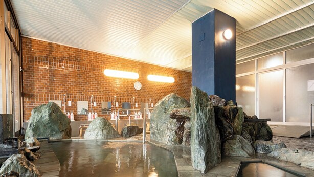 A spa area with a brick wall, large rocks, and a stone pool. - Shiozaki Onsen Awajishima kaijyo Hotel (Minamiawaji)