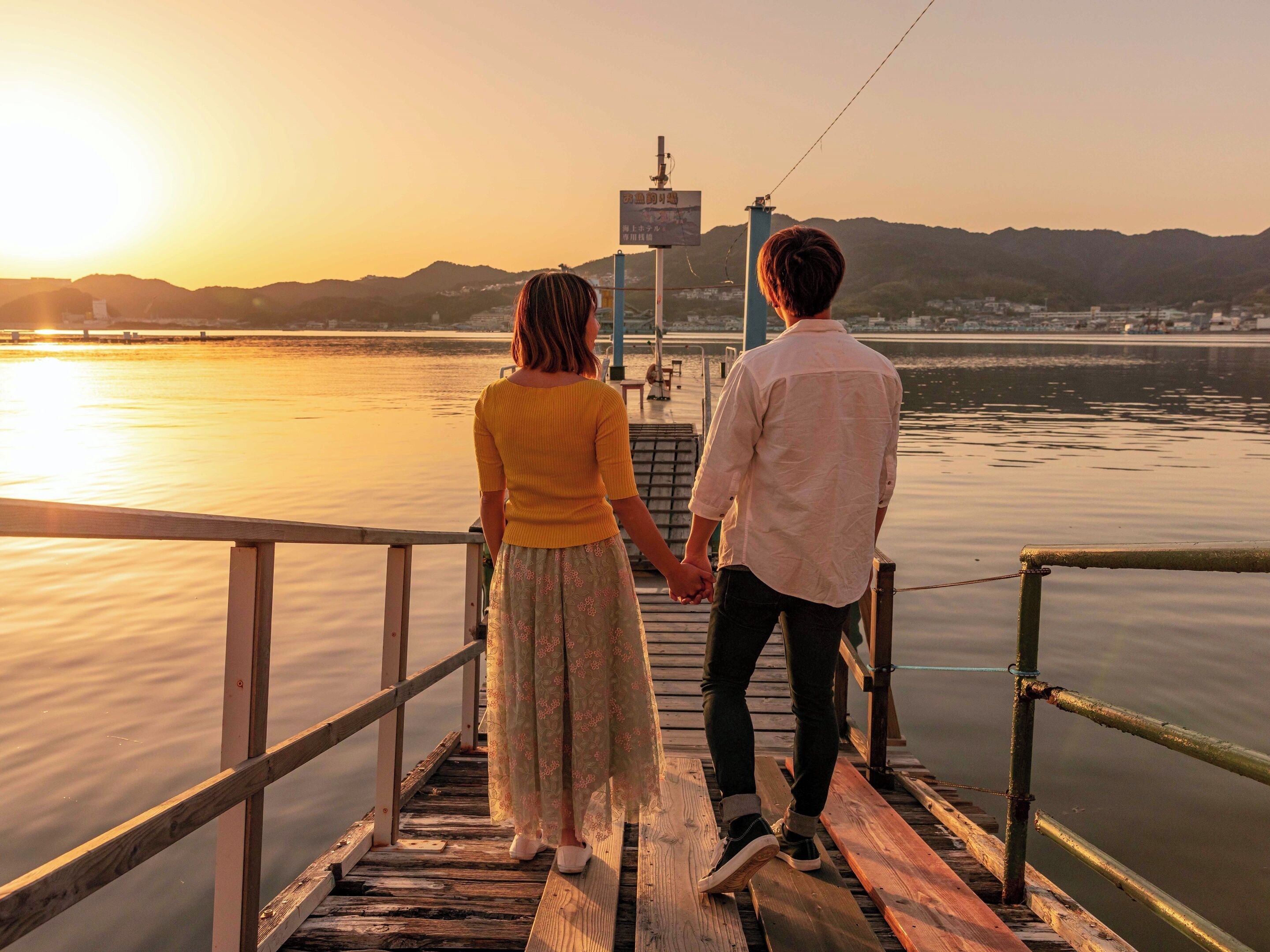 Une jetée en bois s’étendant au-dessus d’une étendue d’eau calme, avec un coucher de soleil en arrière-plan.