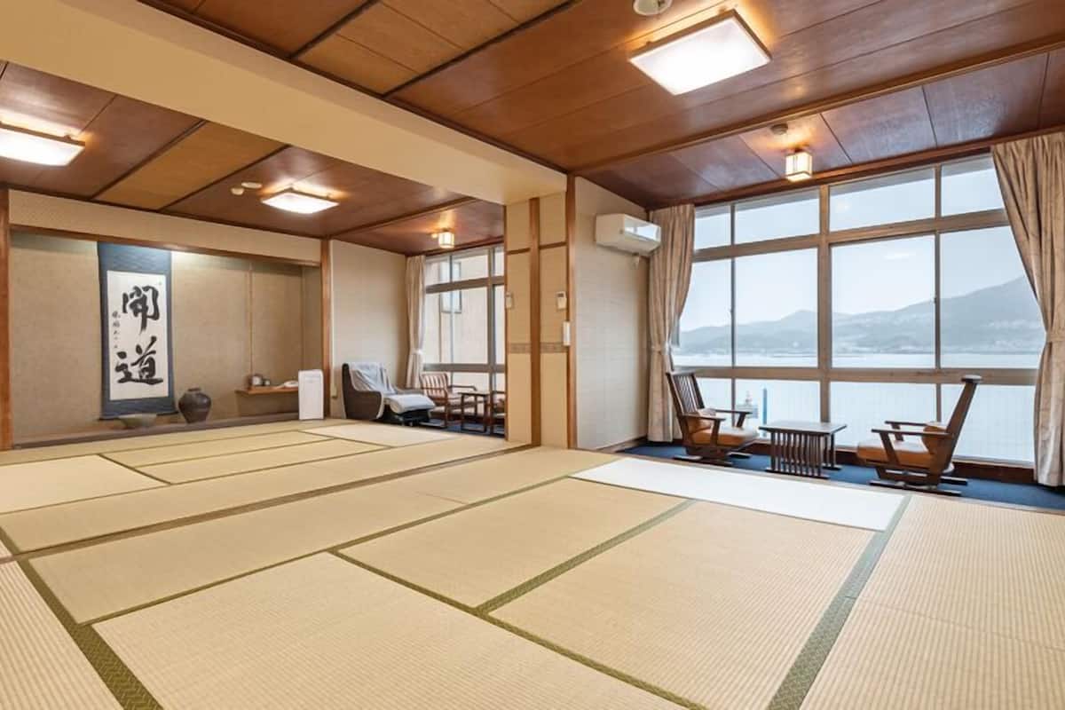Una habitación con tatami y vistas al mar, techo de madera y decoración tradicional japonesa.