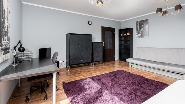 A modern bedroom with a desk, chair, wardrobe, and a sofa. - Podgórze Standard Studio (Kraków)