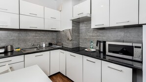 A modern kitchen with white cabinets, a black countertop, and a built-in microwave.