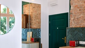 Uma cozinha moderna com parede de tijolos, uma porta verde e um espelho redondo refletindo o ambiente.