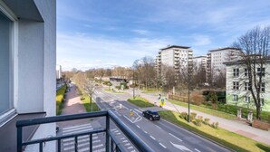 Une rue résidentielle bordée d’immeubles d’appartements modernes, avec un passage piéton et un ciel dégagé.