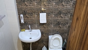 A small bathroom with a sink, toilet, and a water heater mounted on the wall. - Bunk house villa (Noida)