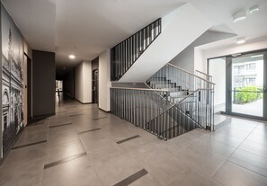 A modern interior with a staircase, tiled flooring, and a mural on the wall.