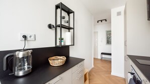 Een moderne keuken met een waterkoker, een mand en een plank met potten.