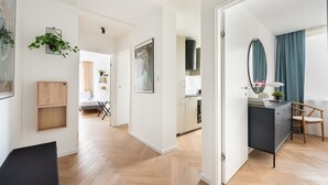 Un appartement moderne comprenant une cuisine, un coin repas et un salon avec un canapé noir et un meuble en bois.
