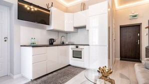 Een moderne keuken met witte kasten, een inbouwoven en een flatscreen televisie boven de aanrecht.